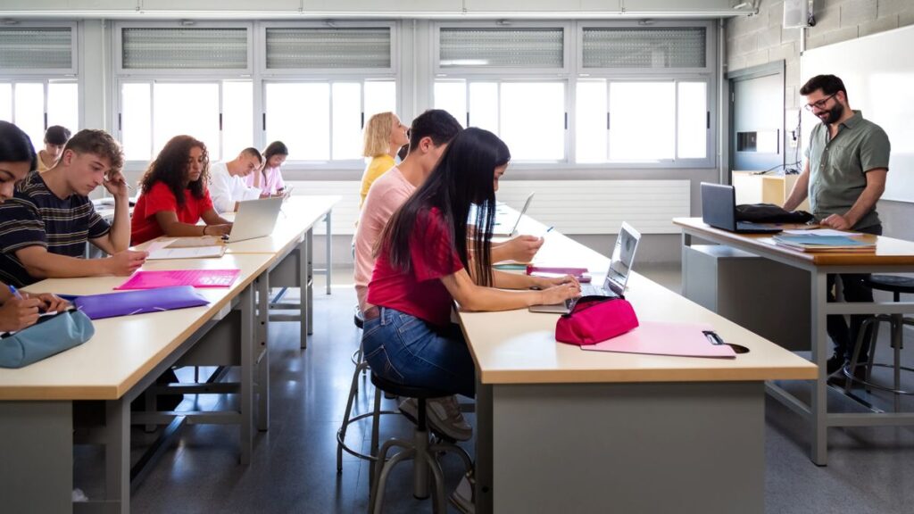 Side view of group of multiracial students studying and using laptops in class with male teacher. Education concept. (Side view of group of multiracial students studying and using laptops in class with male teacher. Education concept., ASCII, 117 comp